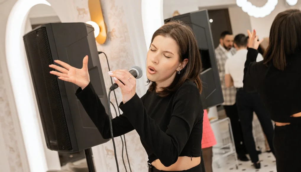 Martyna dainuoja su mikrofonu vokalo pamokoje